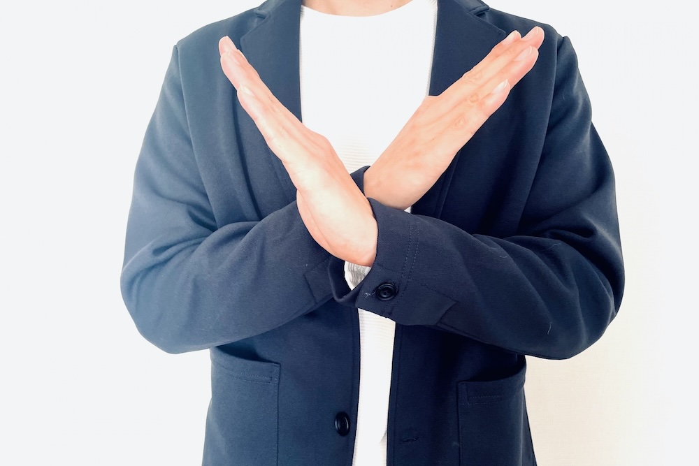 胸元でばつ印を組む男性