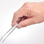ピンセットで鍵をつまみ出している男性